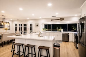 A modern kitchen with a central island, bar stools, a refrigerator, and a dining area with a chandelier. - 25% Off July 20-23! Perfect 4 Families Pool, Spa* (Temecula)