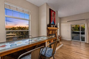 Un comedor con mesa de vidrio, sillas, chimenea y vistas al exterior.