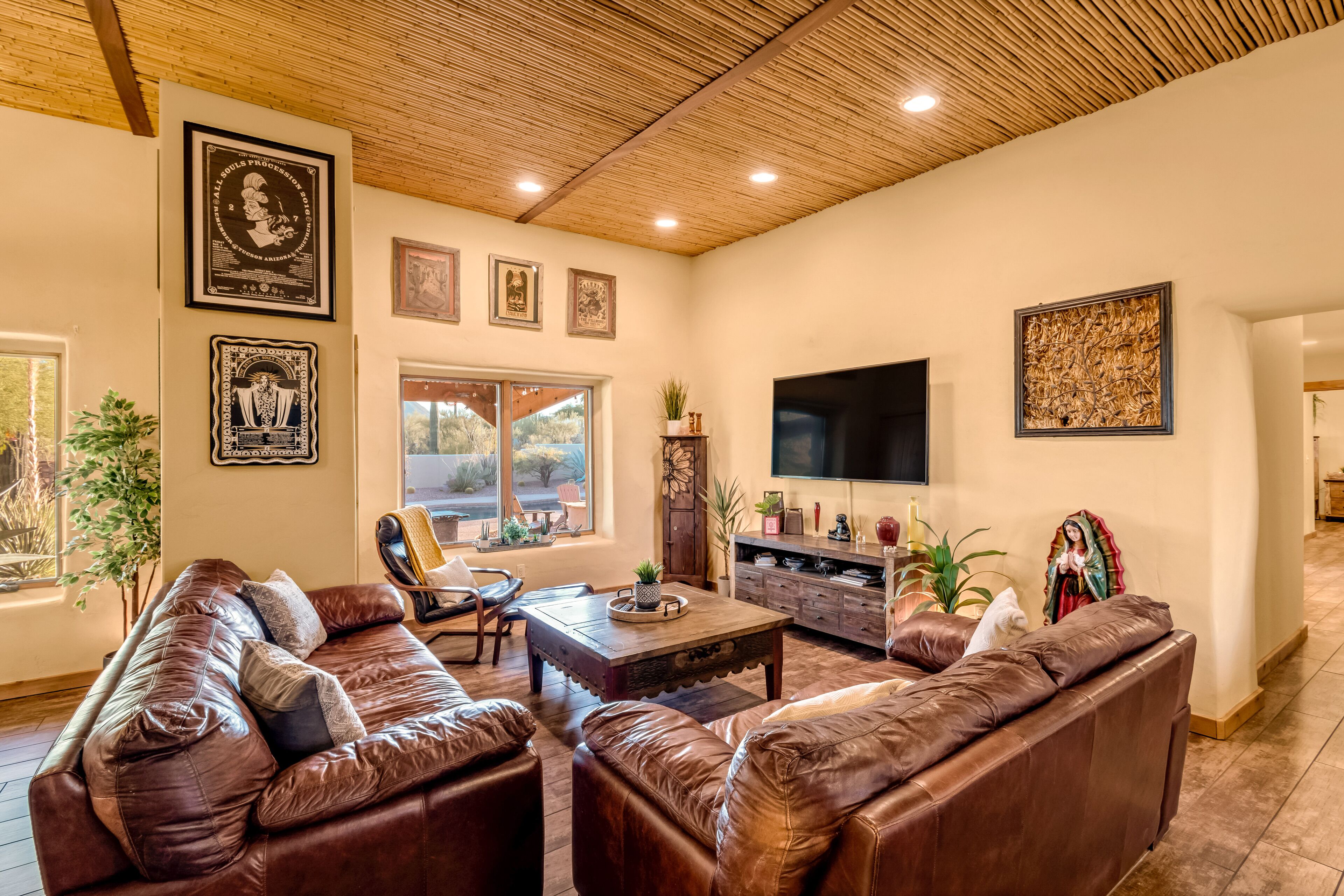 Una sala de estar con sofás de cuero, una mesa de centro de madera y un televisor de pantalla plana.