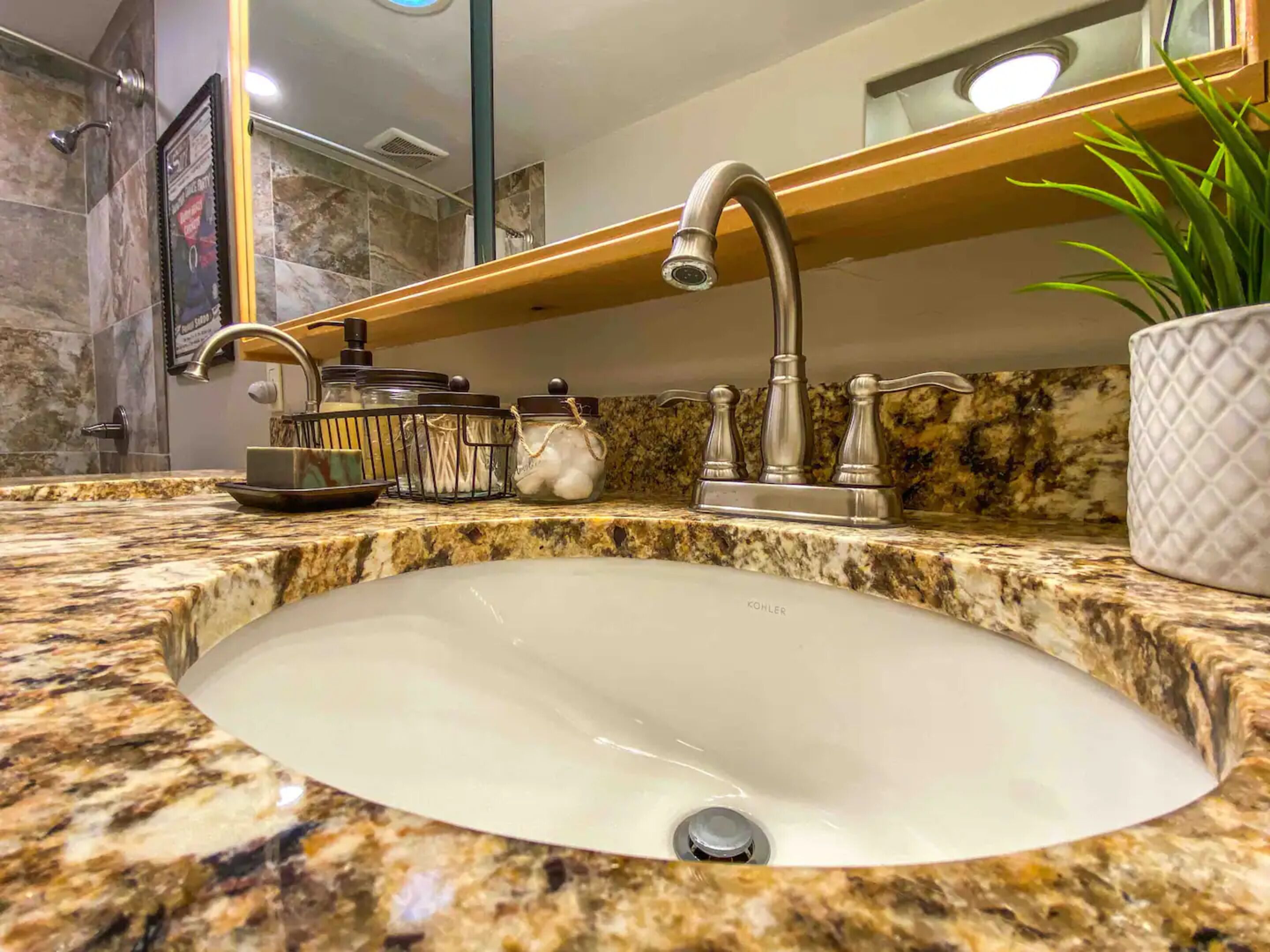 A bathroom with a granite countertop, a white sink, a modern faucet, and a mirror above the sink.