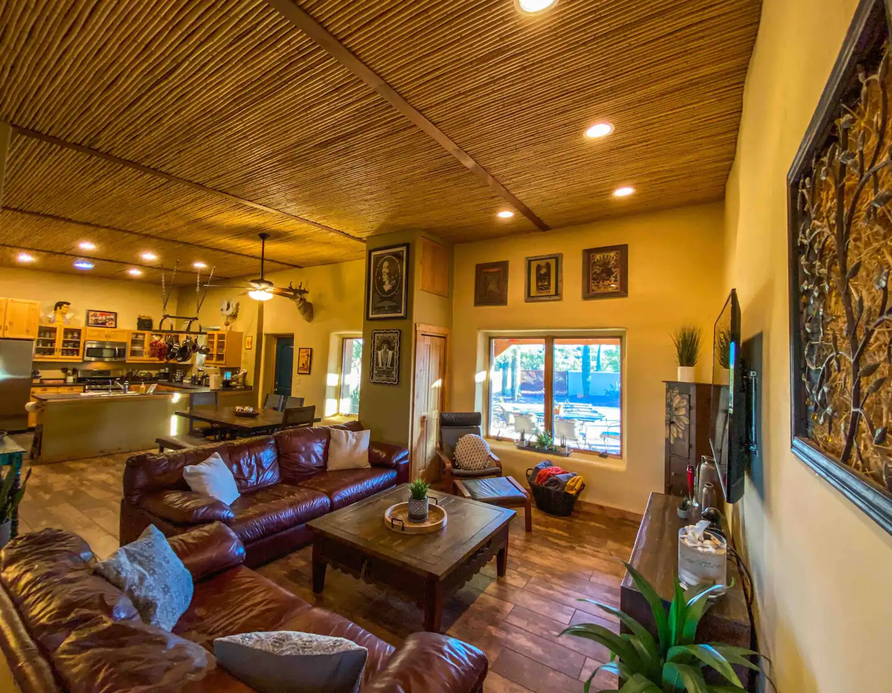 A spacious living area with leather sofas, a wooden coffee table, and a large window offering a view of the outdoors.