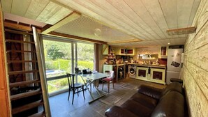 Een gezellige keuken met een eethoek, een ingebouwde wasmachine en een groot raam met uitzicht op een tuin.