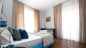 Ein modernes Schlafzimmer mit Bett, Vorhängen, einem Nachttisch und einem Wandbild.