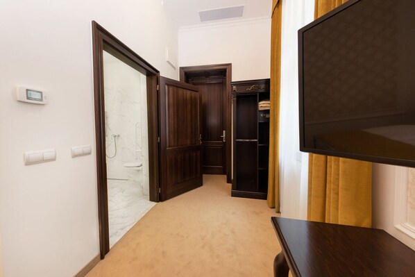 A hallway with a wooden door, a white wall thermostat, and a beige carpet. - Boutique Hotel Gaia (Kecskemet)
