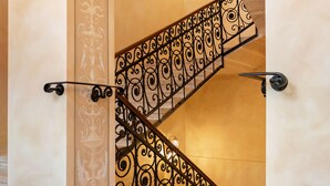 Un escalier avec des rampes en métal noir ouvragé et un sol à motifs.