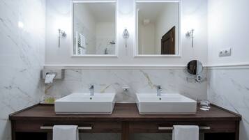 A bathroom with two sinks, marble walls, and a wooden vanity.