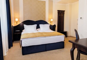 Una habitación de hotel con una cama grande, dos lámparas de noche, una mesita de noche de madera, un escritorio y una silla.