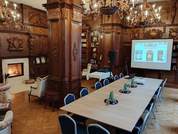 A conference room with a long table, chairs, a projector screen, and a fireplace. - Boutique Hotel Gaia (Kecskemet)