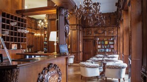 Un hall d’entrée luxueux, agrémenté de boiseries sculptées, d’un imposant lustre et d’un comptoir de réception avec une horloge.
