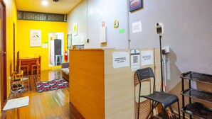 A hotel lobby with wooden flooring, a reception desk, a seating area with chairs, and a small table. - LOFT WATERFRONT KUCHING (Kuching)