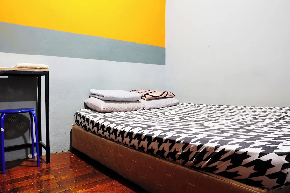 A room with a bed, a small table, and a stool.