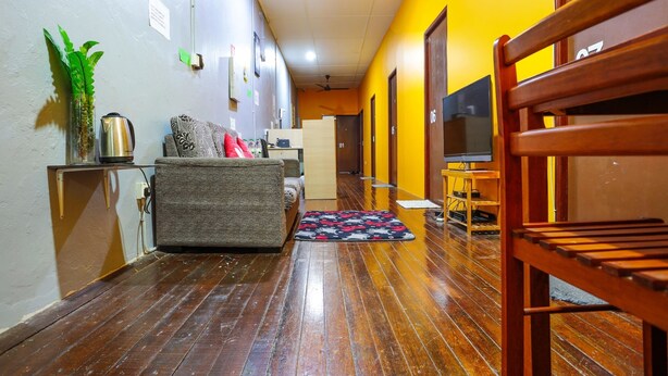 A hallway with a sofa, a coffee table, a TV, and a wooden chair. - LOFT WATERFRONT KUCHING (Kuching)