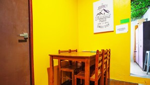A small dining area with a wooden table and chairs, a door, and a poster on the wall. - LOFT WATERFRONT KUCHING (Kuching)