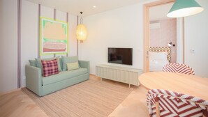 A living room with a sofa, TV, and a dining area with chairs. - Allegro Boutique Apartment B (Porto)