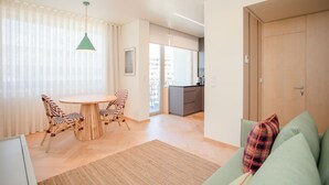 A modern living room with a dining area, a sofa, and a kitchen in the background. - Allegro Boutique Apartment B (Porto)