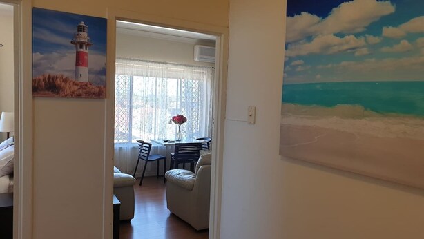 Een kamer met een eethoek, een bank en een schilderij van een vuurtoren.