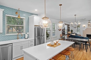 Una cocina moderna con una isla central, electrodomésticos de acero inoxidable y un salpicadero de azulejos azules.