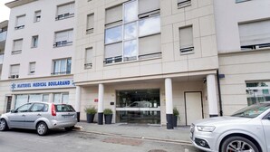 Un edificio médico con un letrero que dice "Materiel Medical Boularand" y dos coches estacionados frente a él.