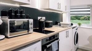 A modern kitchen with a built-in microwave, toaster, coffee maker, and oven. - Stunning 2-bed Apartment in Banbury (Banbury)