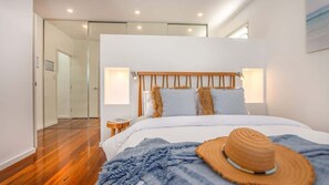 A modern bedroom with a wooden headboard, a large bed, and a nightstand. - Verano (Casuarina)
