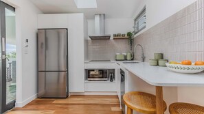 Eine moderne Küche mit einem Edelstahl-Kühlschrank, einem Einbauofen und einer weißen Arbeitsplatte.