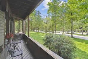 A covered porch with a view of a well-maintained lawn and trees.