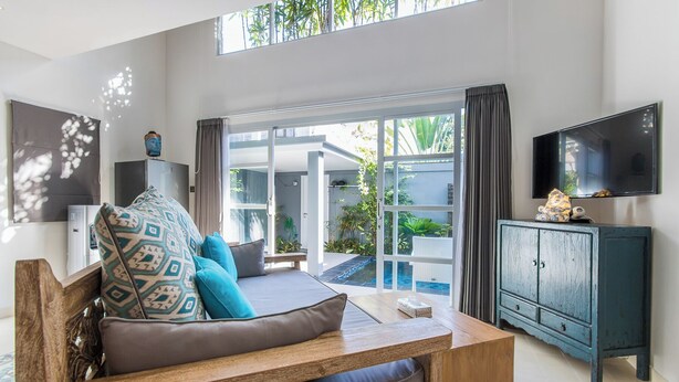 A modern living room with a sofa, a wooden coffee table, a TV, and a view of a pool and garden through large glass doors. - One bedroom private pool romantic villa (Bali)