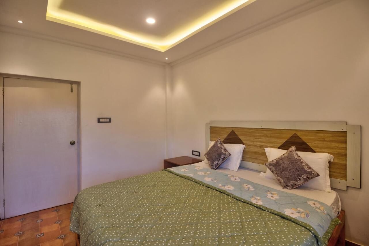 A bedroom with a bed, a nightstand, a wooden headboard, and a door.
