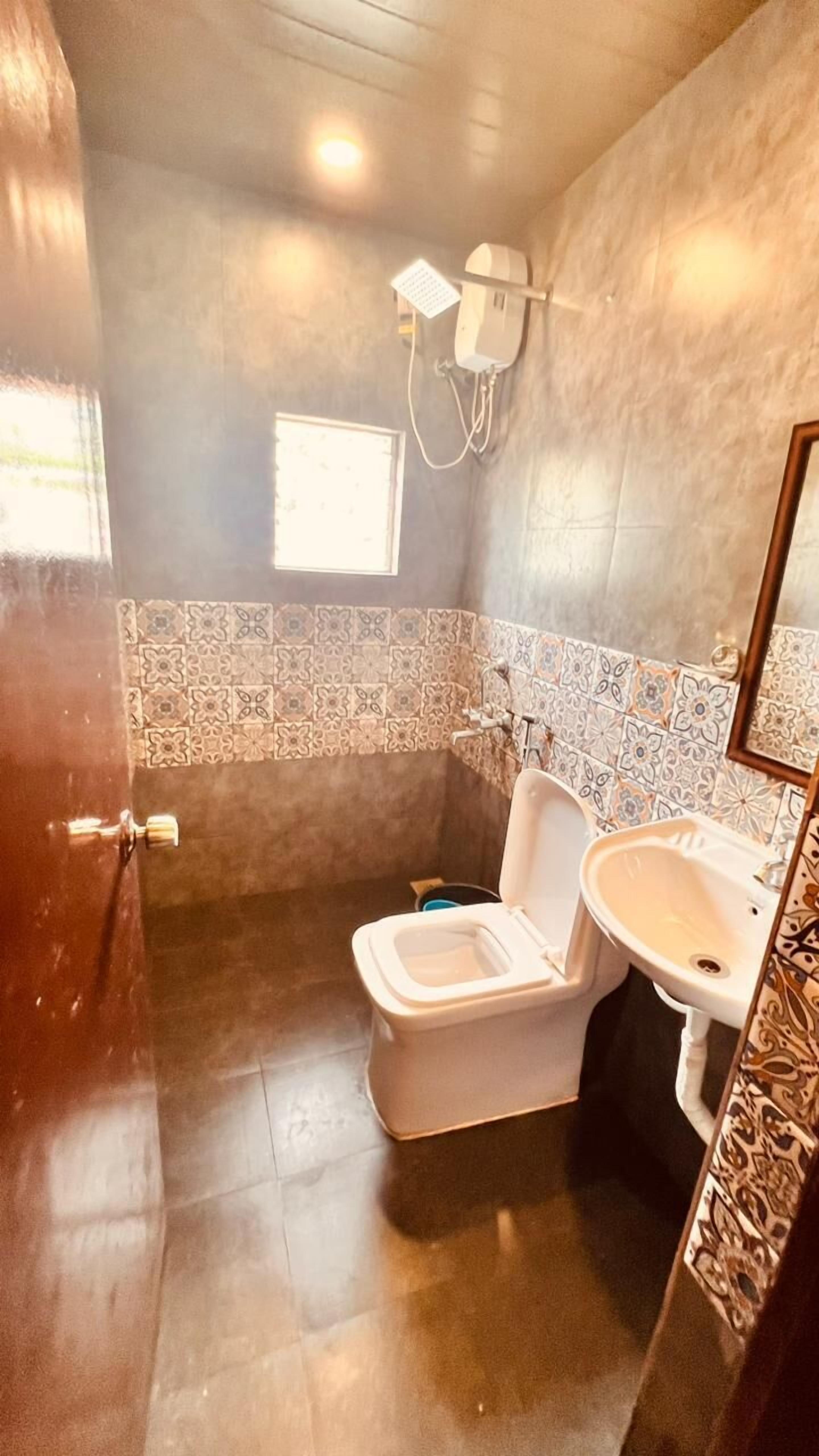 A bathroom with a toilet, sink, and a small window.