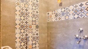 Een badkamer met toilet, douche en een wandapparaat.
