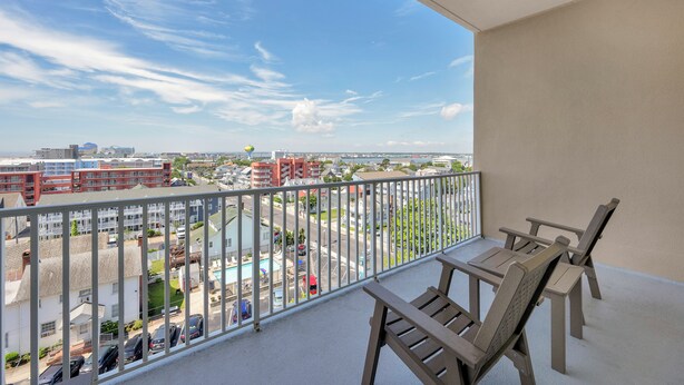 A balcony with a view of a cityscape, including buildings and a road.