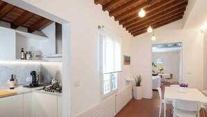 Una cocina moderna con armarios blancos, una estufa y un comedor con una mesa y sillas blancas.