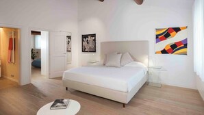 Un dormitorio moderno con una cama grande, una mesita de noche y un cuadro abstracto colgado en la pared.