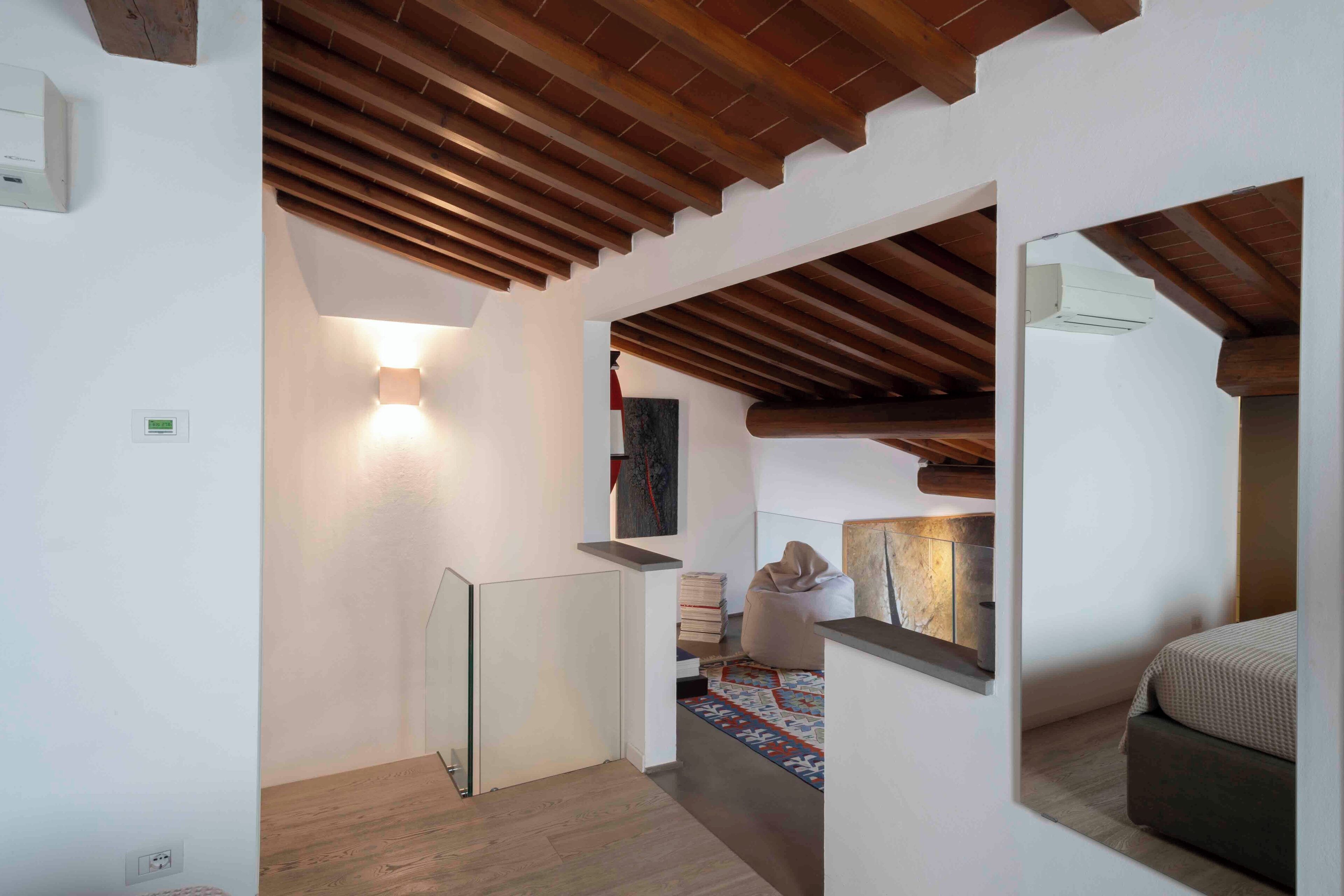 A modern interior with wooden beams, a staircase, and a cozy seating area.