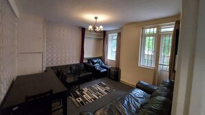 A compact living space with a sofa, a dining table, and a patterned rug. - Charming Three Bedroom 5 Double Bed Apt in London (London)