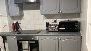 A compact kitchen with grey cabinets, a built-in microwave, a toaster, and a kettle. - Charming Three Bedroom 5 Double Bed Apt in London (London)