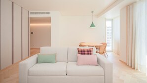 A modern living room with a sofa, pillows, a small table, and a chair.