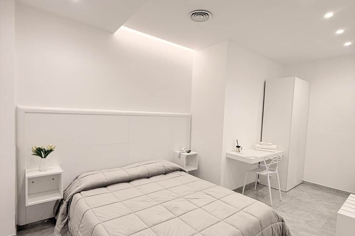 Un dormitorio moderno con cama, mesitas de noche, un escritorio y una silla.
