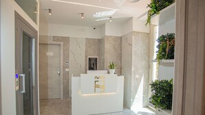 A reception area with a marble reception desk, a potted plant, and a glass door. - Forever luxury rooms (Castellammare di Stabia)