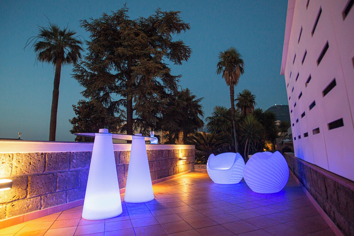 Terraza al aire libre con macetas iluminadas y un muro de piedra.