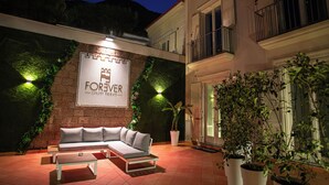 An outdoor seating area with a sofa and coffee table, a potted plant, and a sign that reads "FOREVER". - Forever luxury rooms (Castellammare di Stabia)