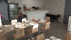 A dining area with a long table set for a meal, a kitchen area with a brick wall, and a WC sign on the left. - H. Central Funchal (Madeira)
