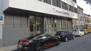 A building with a sign reading "Hostel CENTRAL" and a black sports car parked in front. - H. Central Funchal (Madeira)