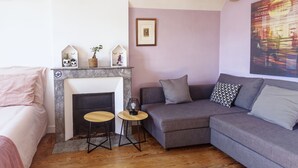 Una sala moderna con chimenea, un sofá, una mesita y un cuadro en la pared.