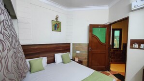 A hotel room with a bed, a green and white bedspread, a wooden headboard, a green door, and a small window. - Harish Guest House -Railway Station Road (Chandigarh)