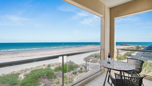 A balcony with a table and chairs overlooking a beach and ocean. - Belle Escapes - Beachfront Balcony Glenelg (Glenelg)