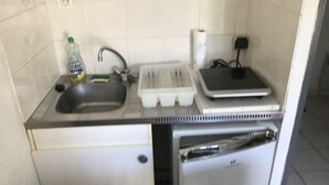 Cozinha compacta com pia, uma pequena geladeira, micro-ondas e torradeira.