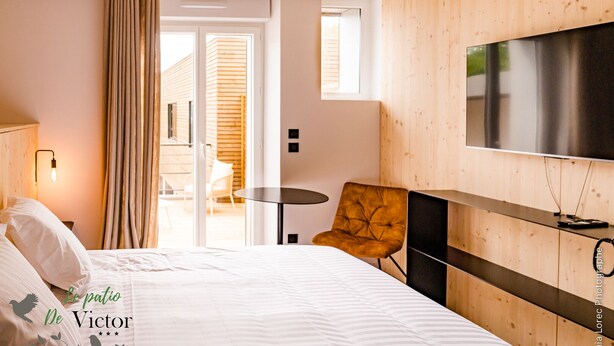Una habitación de hotel con cama, televisor, una mesita y una silla.