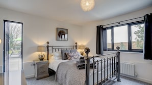 Une chambre à coucher avec un lit, des tables de chevet, une lampe, un radiateur et une fenêtre avec des rideaux.