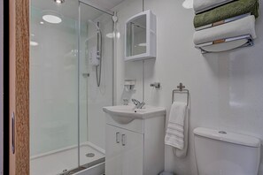 Uma casa de banho moderna com chuveiro em cabine de vidro, lavatório branco e sanita.